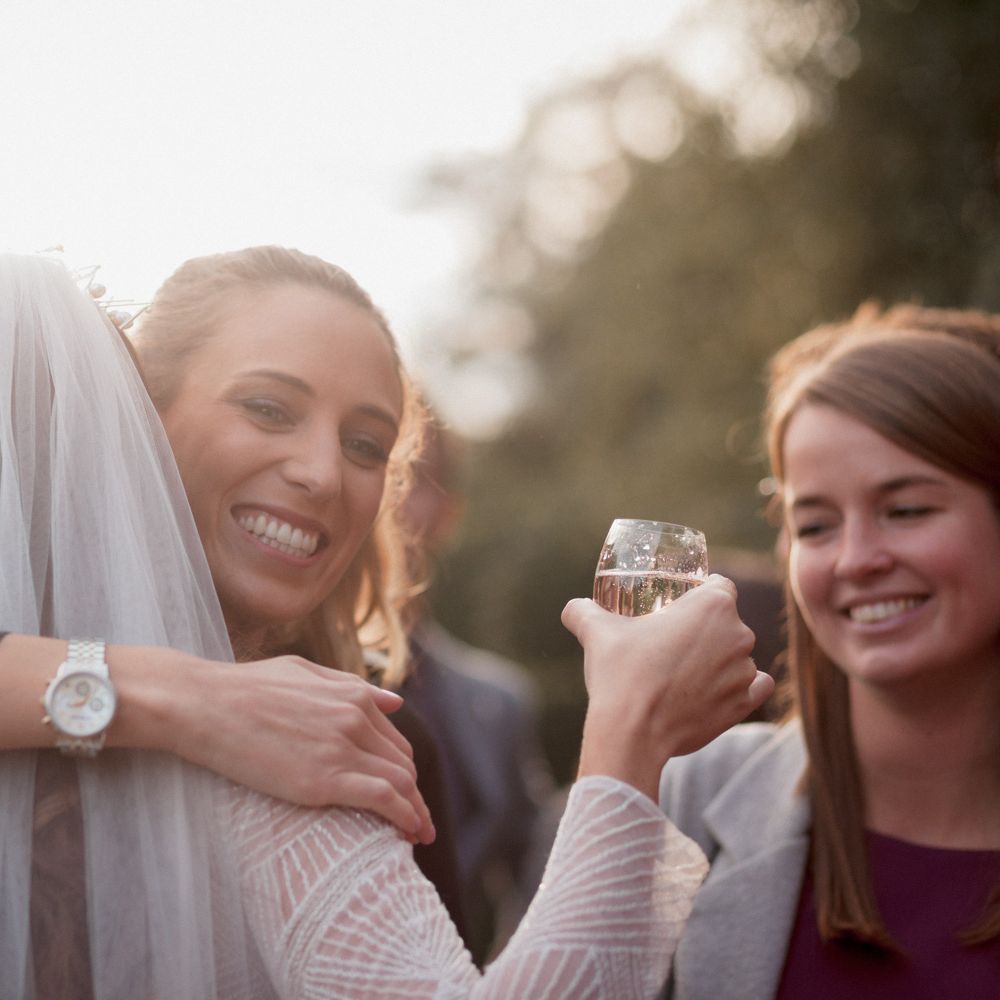 Wedding guest hugging bride wearing veil 