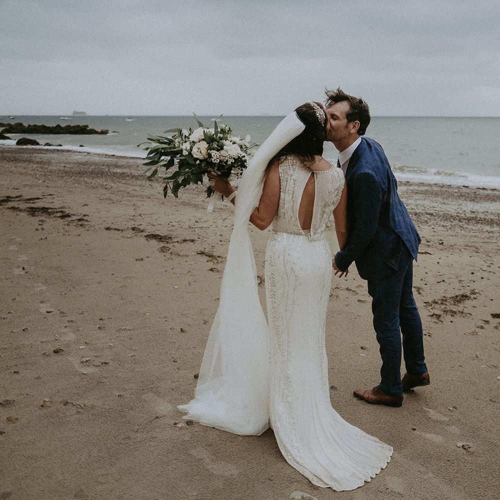 Bride & groom kiss on the beach after wedding ceremony