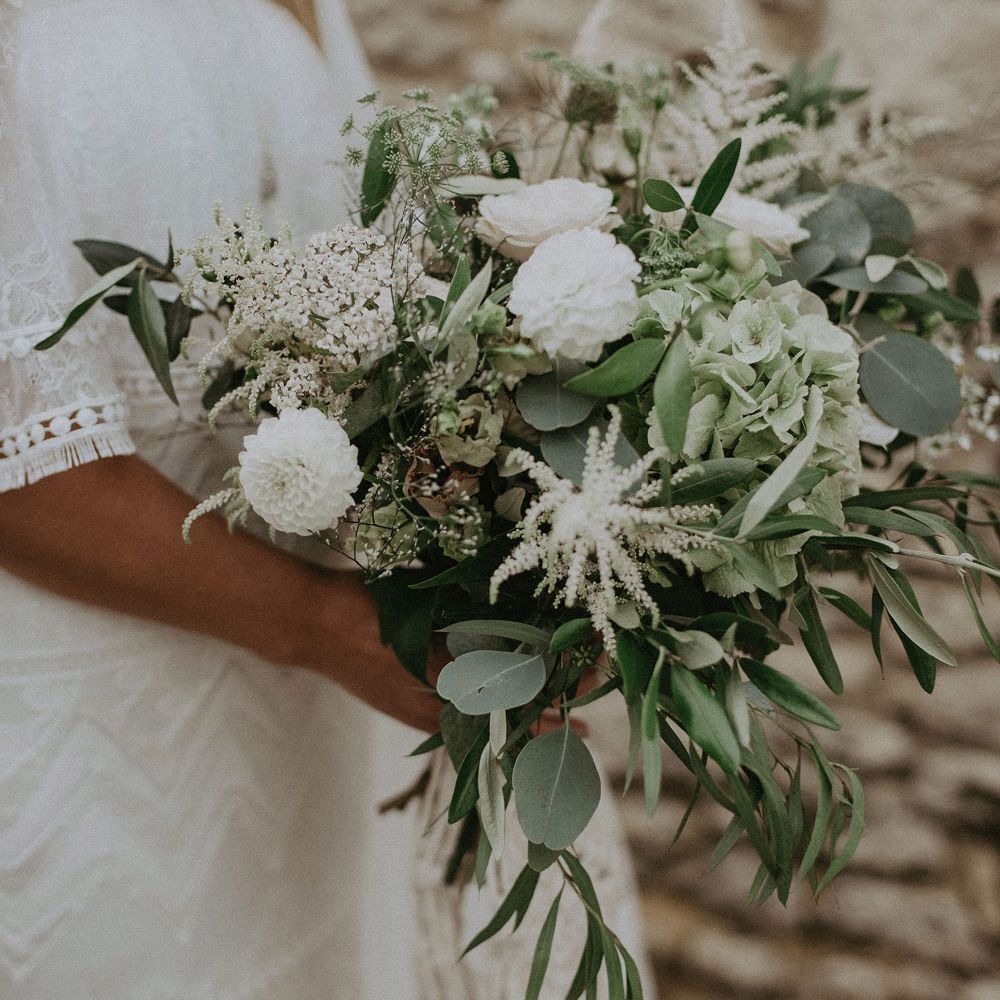Bride in Grace Loves Lace bardot wedding dress holding white and green bridal bouquet at Isle of Wight wedding with macrame wedding decor