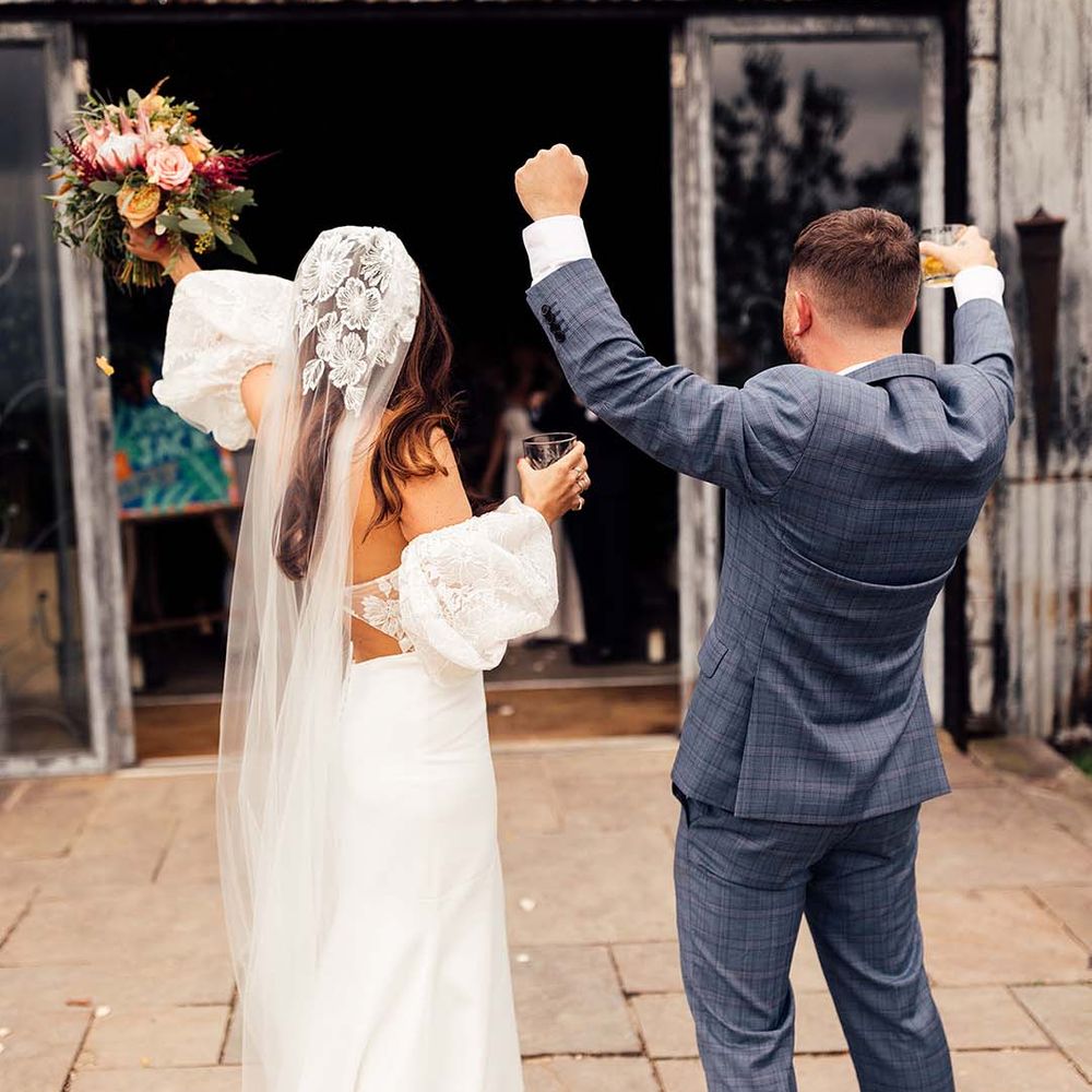 Bride & groom celebrate after ceremony as they hold cocktails 