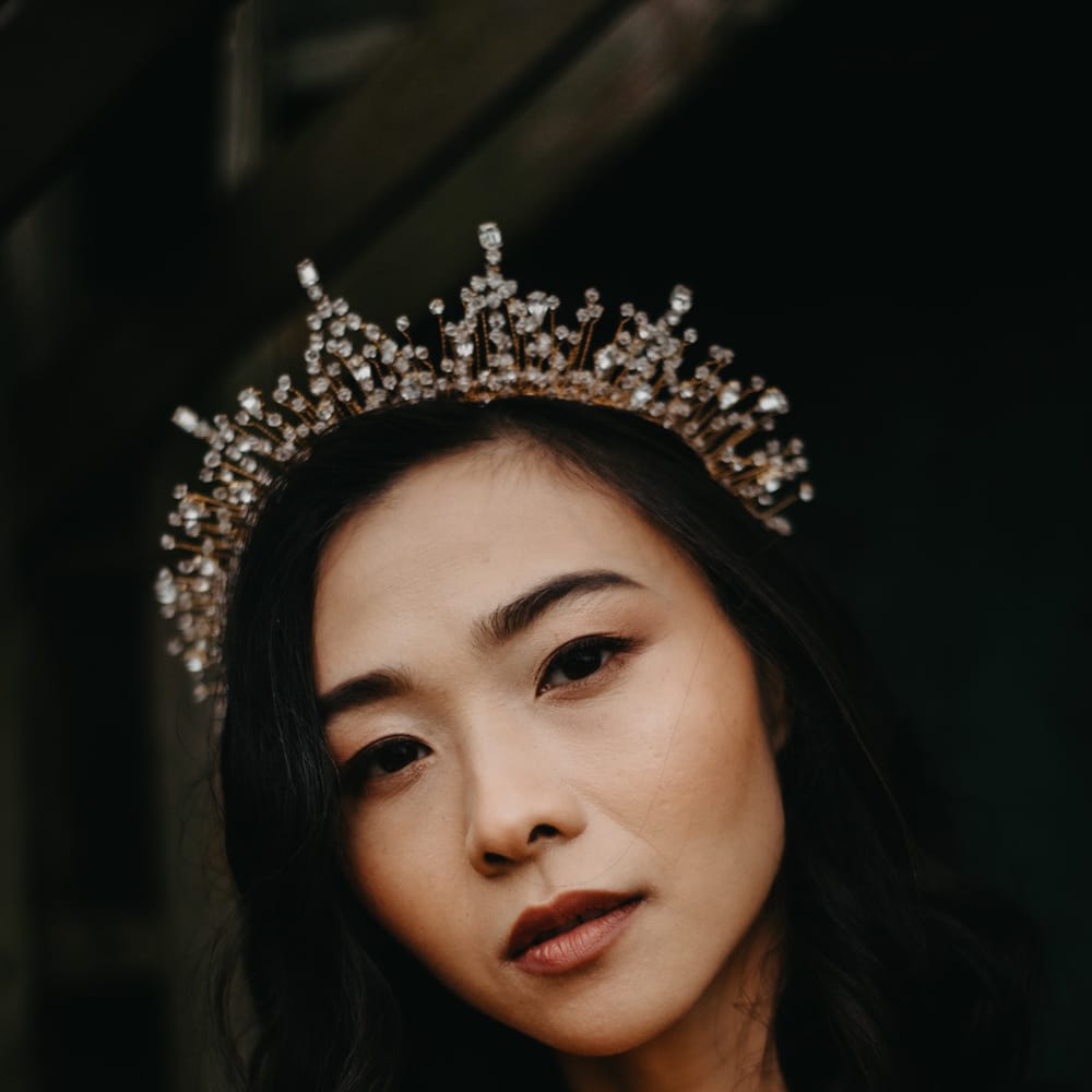Bride with short hair and bejewelled bridal headpiece holds tropical bridal bouquet as she stands in doorway