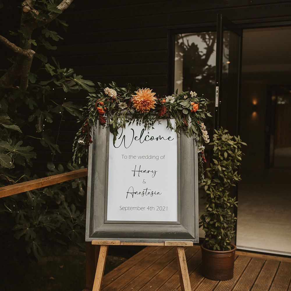 Framed monochrome welcome wedding sign with orange flower decor