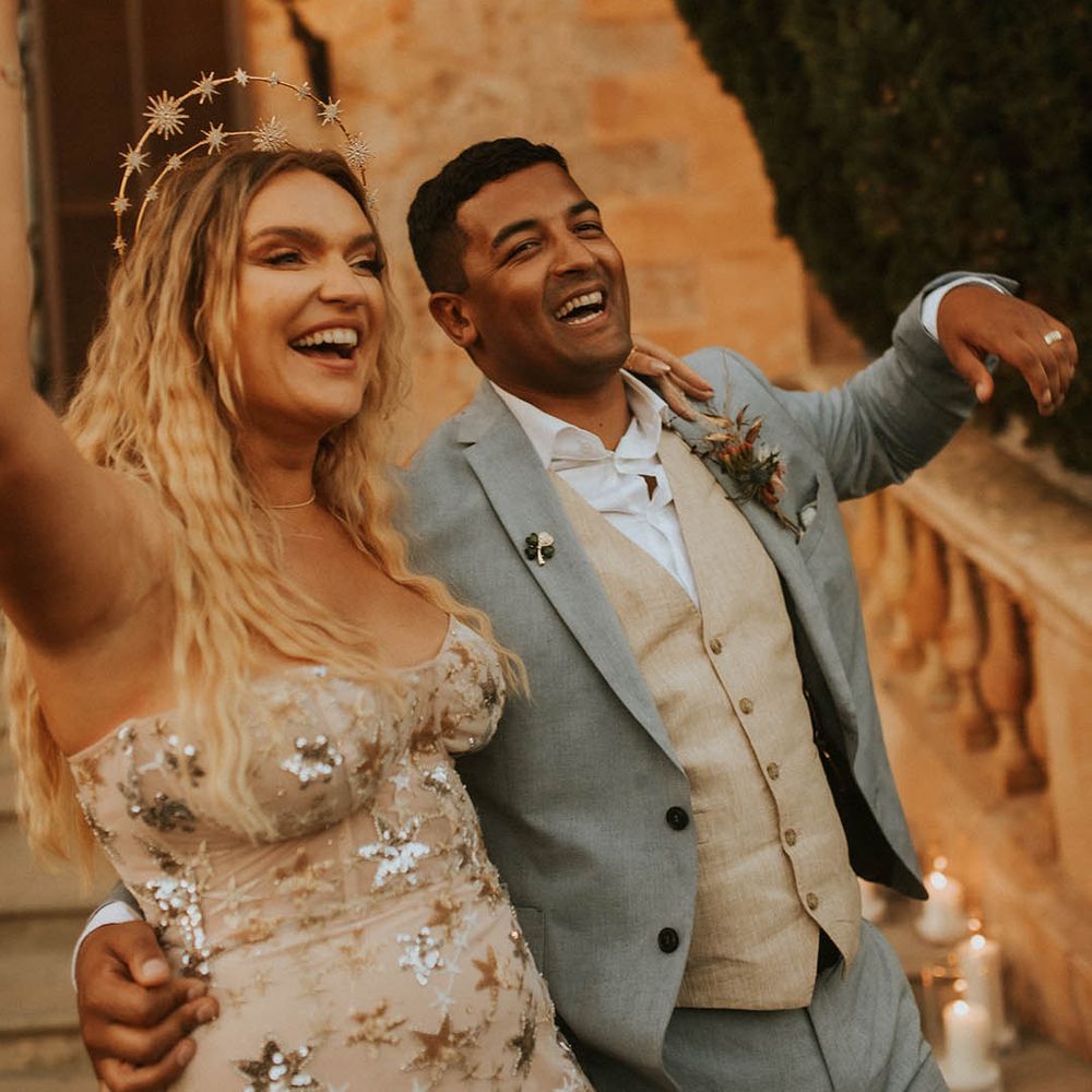 Bride & groom celebrate as they hold champagne bottle and smile