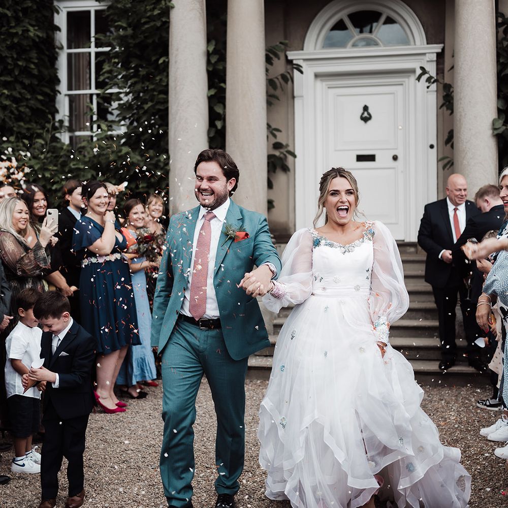 Confetti moment at Iscoyd Park wedding venue with groom in a blue suit and bride in an embroidered Victoria Sanders bespoke wedding dress 