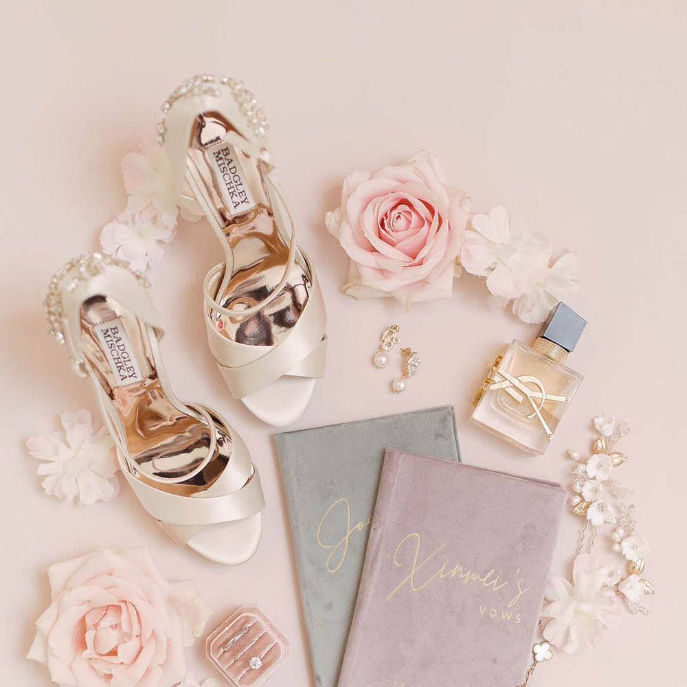 Pale satin wedding shoes beside wedding jewellery and velvet stationery book containing vows