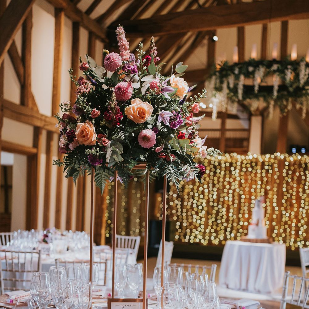 Muted pink tablescape with copper cutlery with tall flower centrepieces