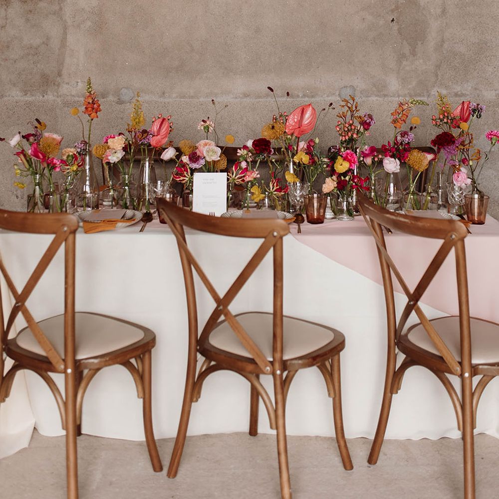 Wedding reception table with flower cloud installation and wildflower stems in bottles table decor 