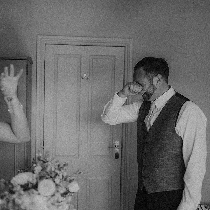 Father of the bride wipes his eyes as he cries seeing the bride for the first time 