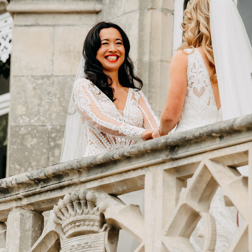 Bride smiles widely as they hold hands together during the ceremony 