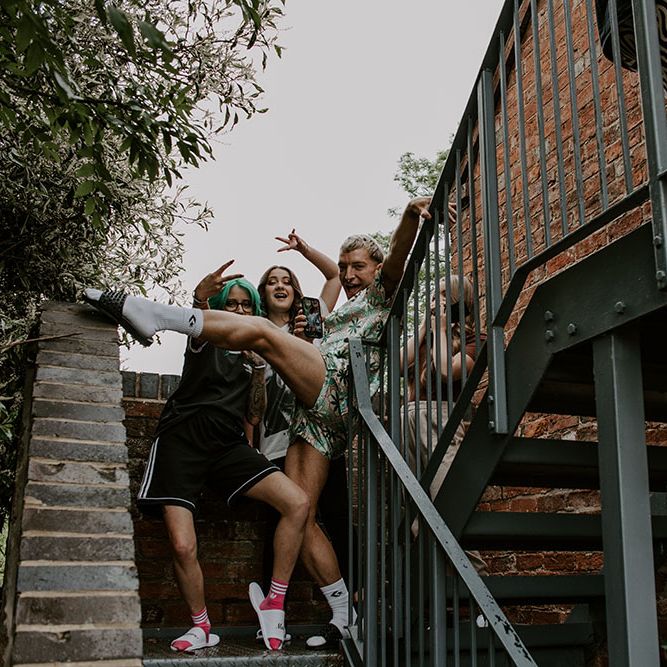 Groom poses with his bridesmaids outdoors on the morning of his wedding day