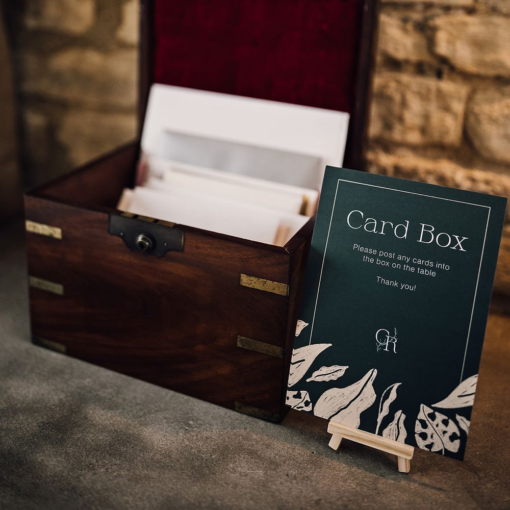 Green and gold sign for the cards next to a wooden box full of cards from the guests 