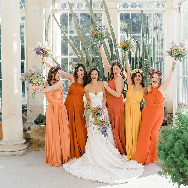 Bride in Emma Beaumont design wedding dress stands with her bridesmaids in ombre styled orange and yellow bridesmaid dresses 