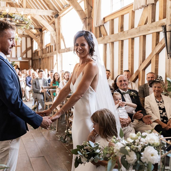 Bride in Grace Loves Lace wedding dress holds her grooms hands during civil ceremony at barn wedding venue 