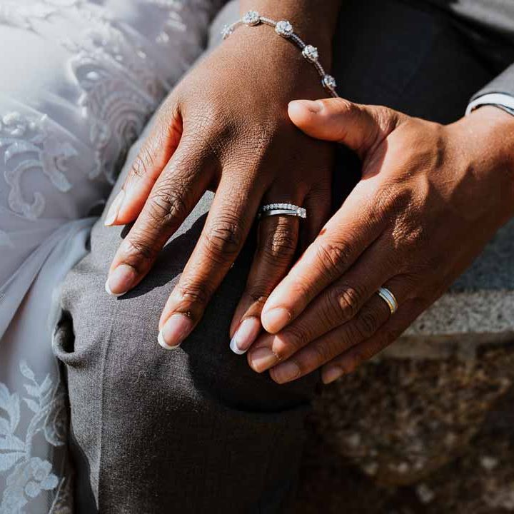Bride wearing silver sparkly wedding bracelet and silver wedding ring and groom wearing black and gold watch with wedding ring