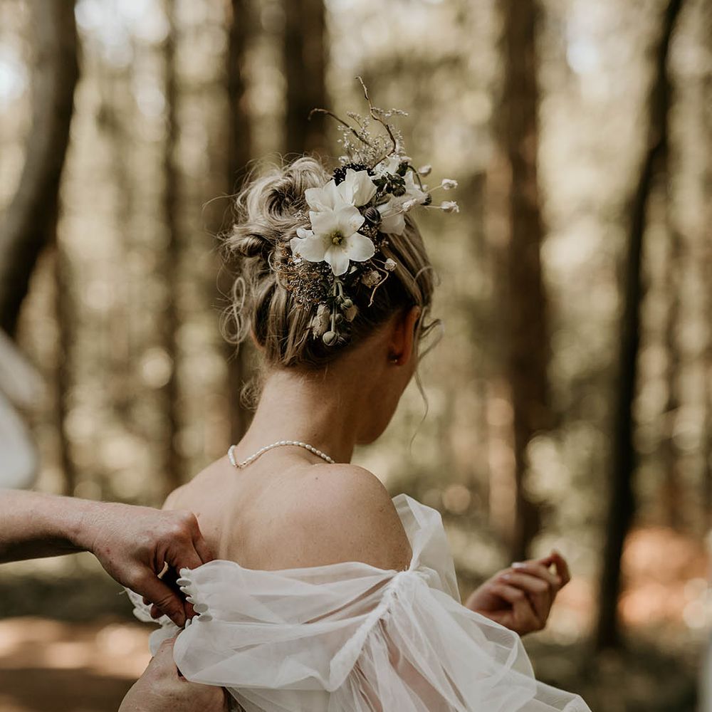Bride in strapless Milla Nova wedding dress with floral embroidered detail with tulle detachable sleeves with white flower hair accessory 