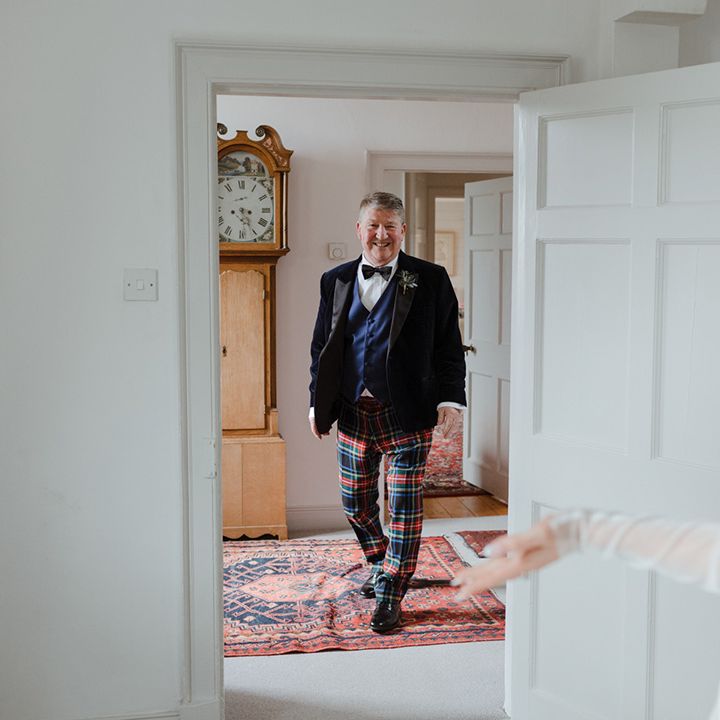 Father of the bride in tuxedo and tartan trousers gets to see the bride 