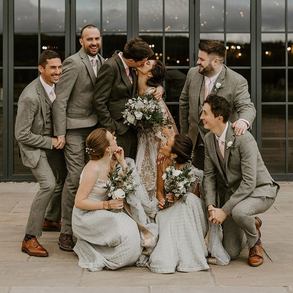 The wedding party pose together in neutral grey wedding outfits with sparkly details 