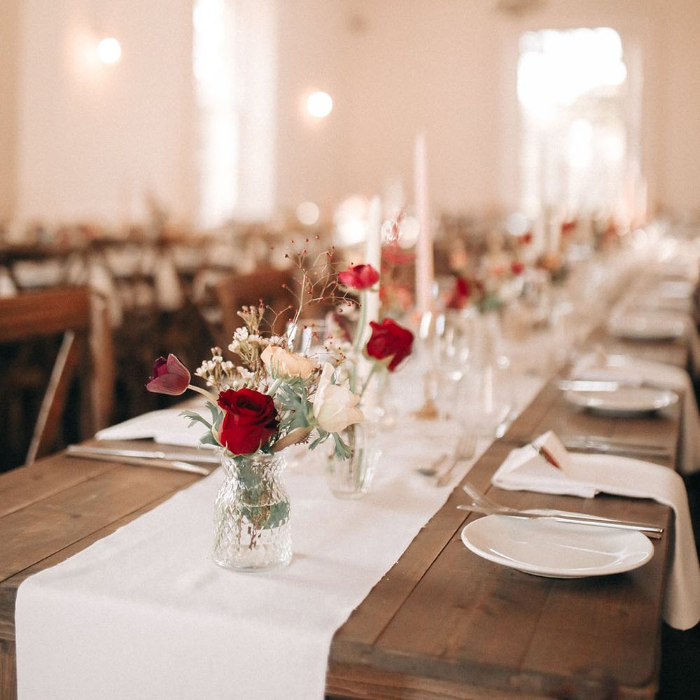 White and red roses in bud vases for Christmas wedding table decorations 