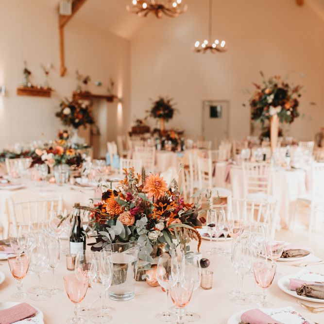 Wedding table decor at Millbridge Court with floral centrepiece, coloured wine glasses and napkins. 