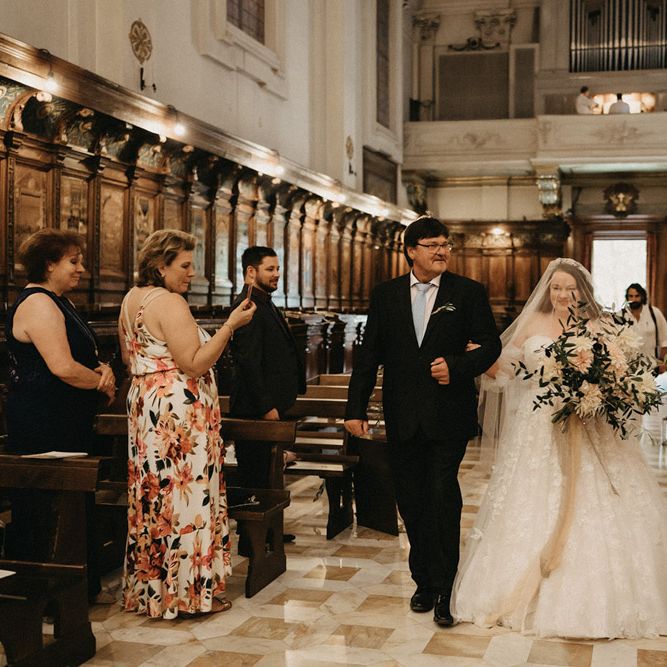 Saskia walks down the aisle with a huge olive bouquet