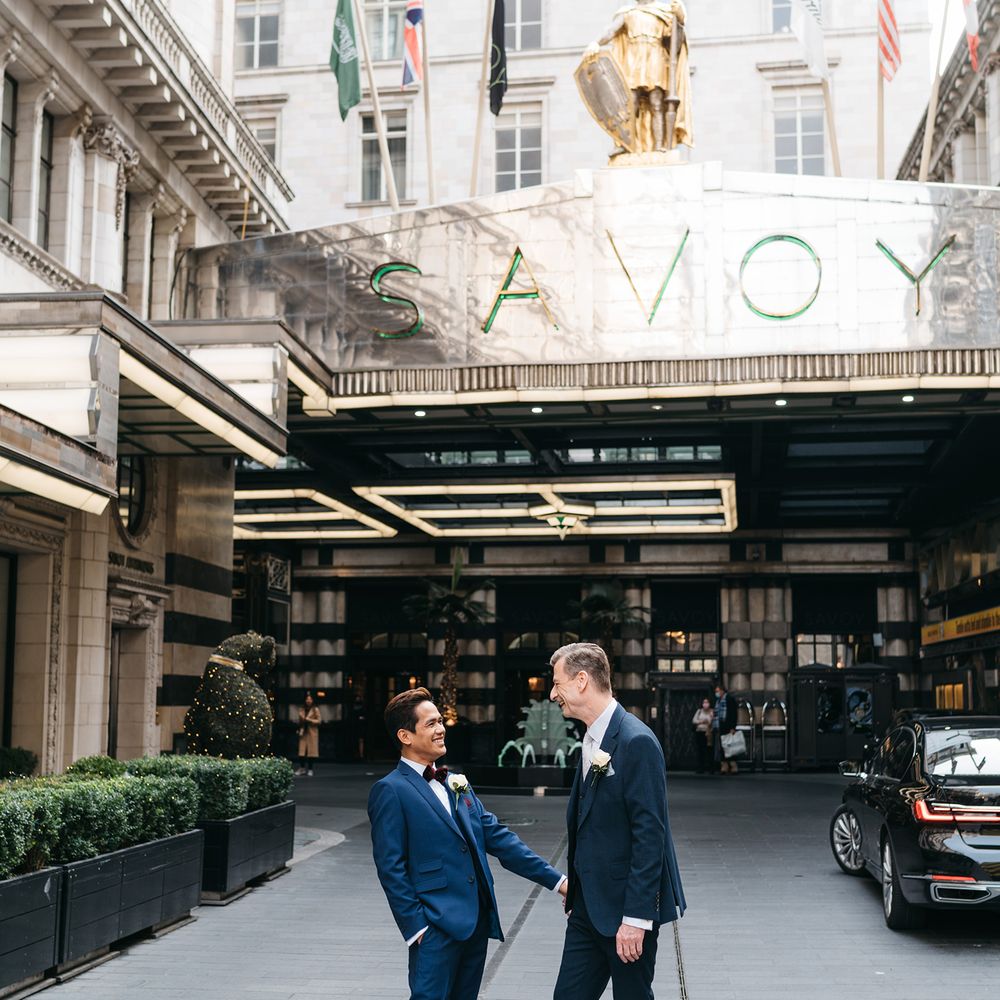 Grooms stand together and smile outside the Savoy hotel