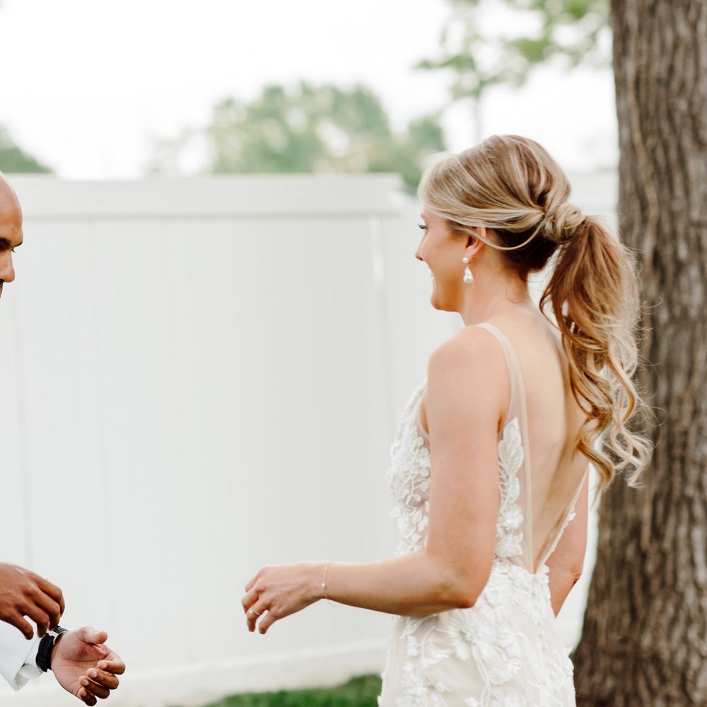 Groom looks amazed at bride in white Made With Love wedding dress for first look at backyard wedding