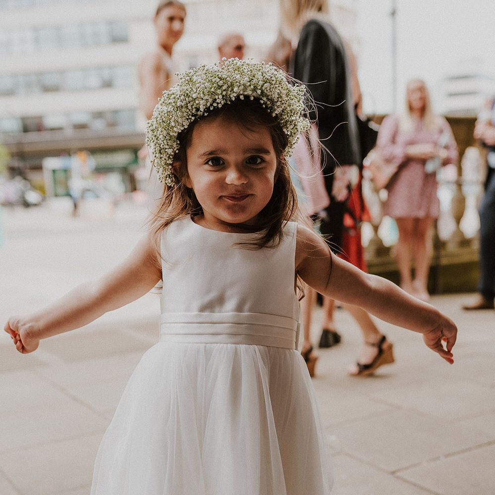 Beautiful flower girl in a white tulle skirt dress with gypsophila flower crown 