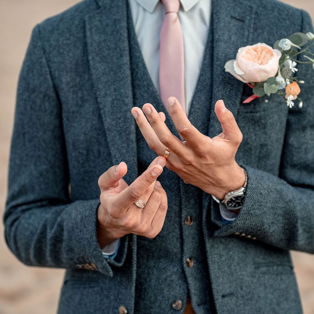 Groom in a three-piece blue wool suit with pale pink tie and peach David Austen Rose buttonhole flower 