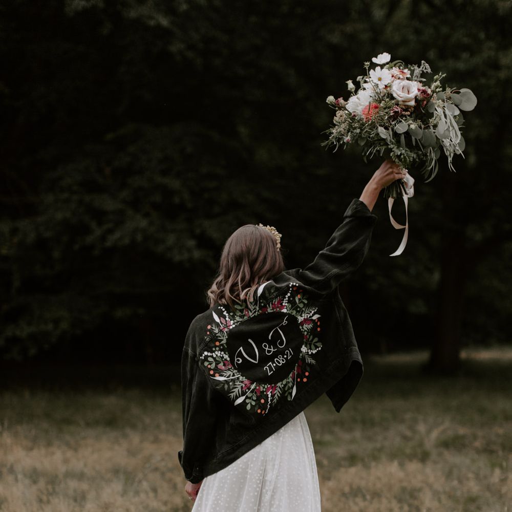 Bride wears personalised black denim jacket with floral illustrations 