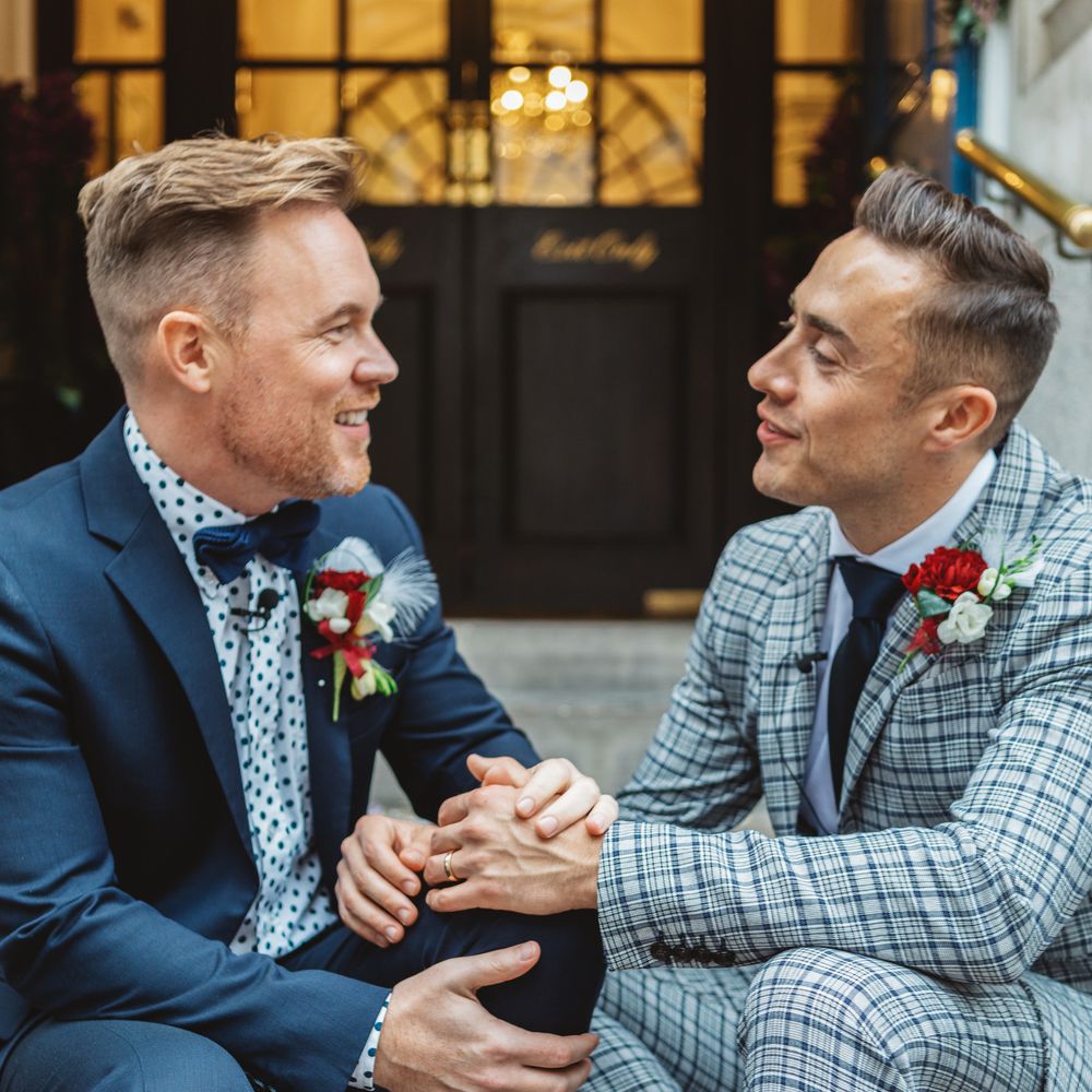 Grooms laugh with one another on their wedding day