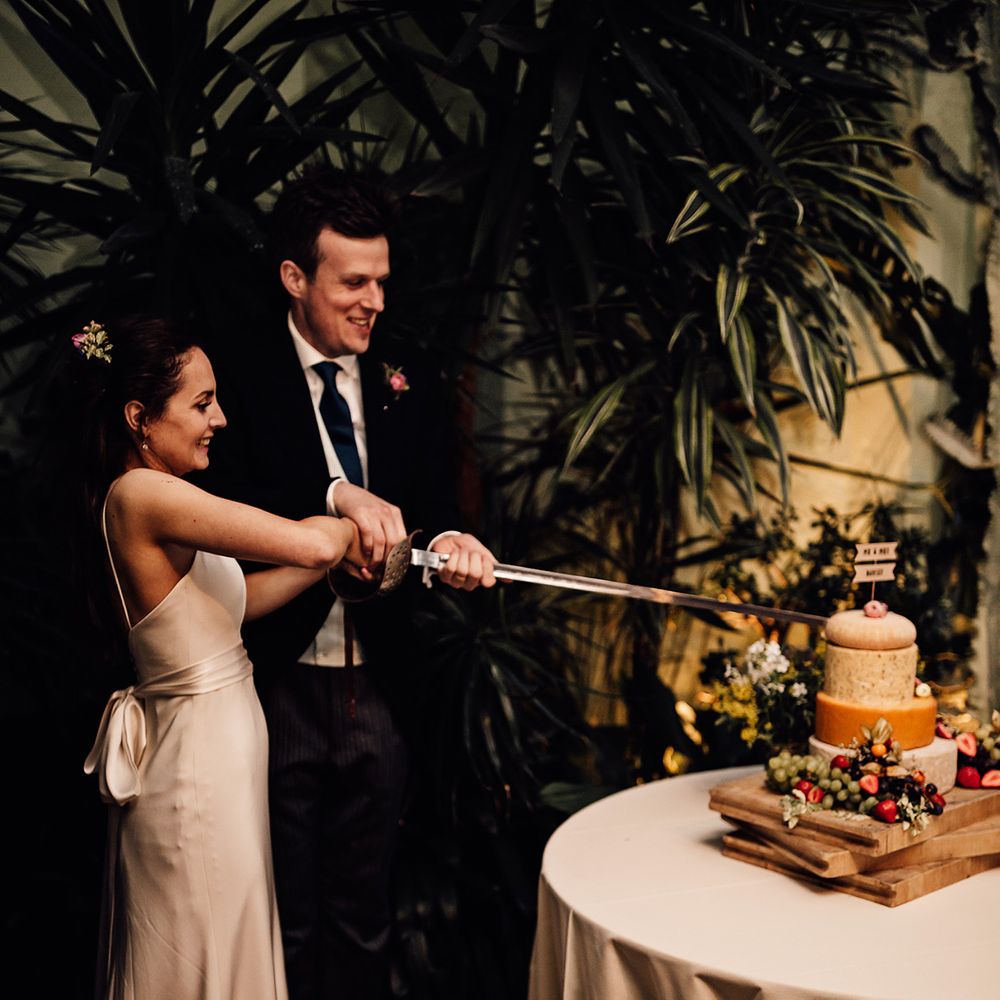 Bride and groom cut their cheese tower with a sword 