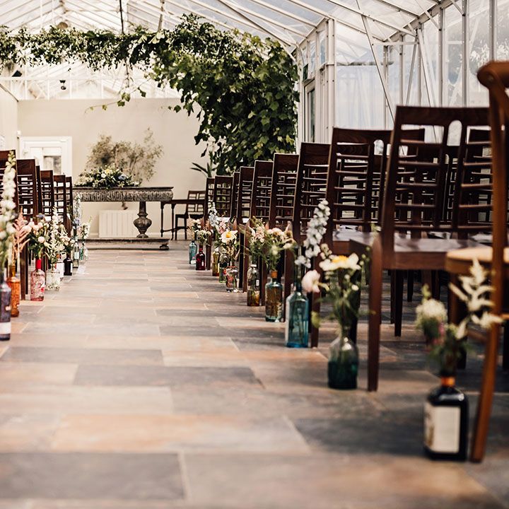 Greenhouse conservatory style ceremony room with glass bottle aisle decoration at Houghton Lodge