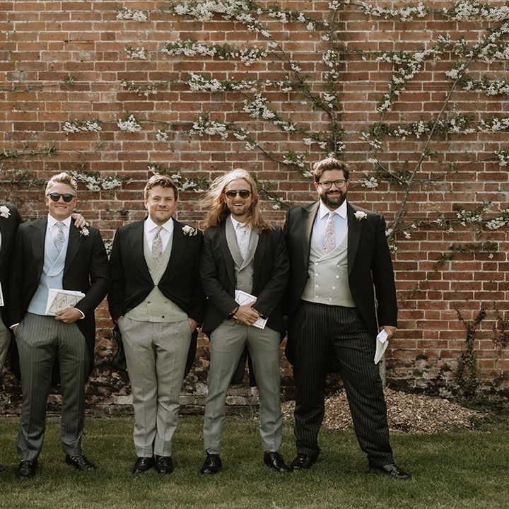 Groom and groomsmen in black morning suit jackets with different colour and style waistcoats and trousers 