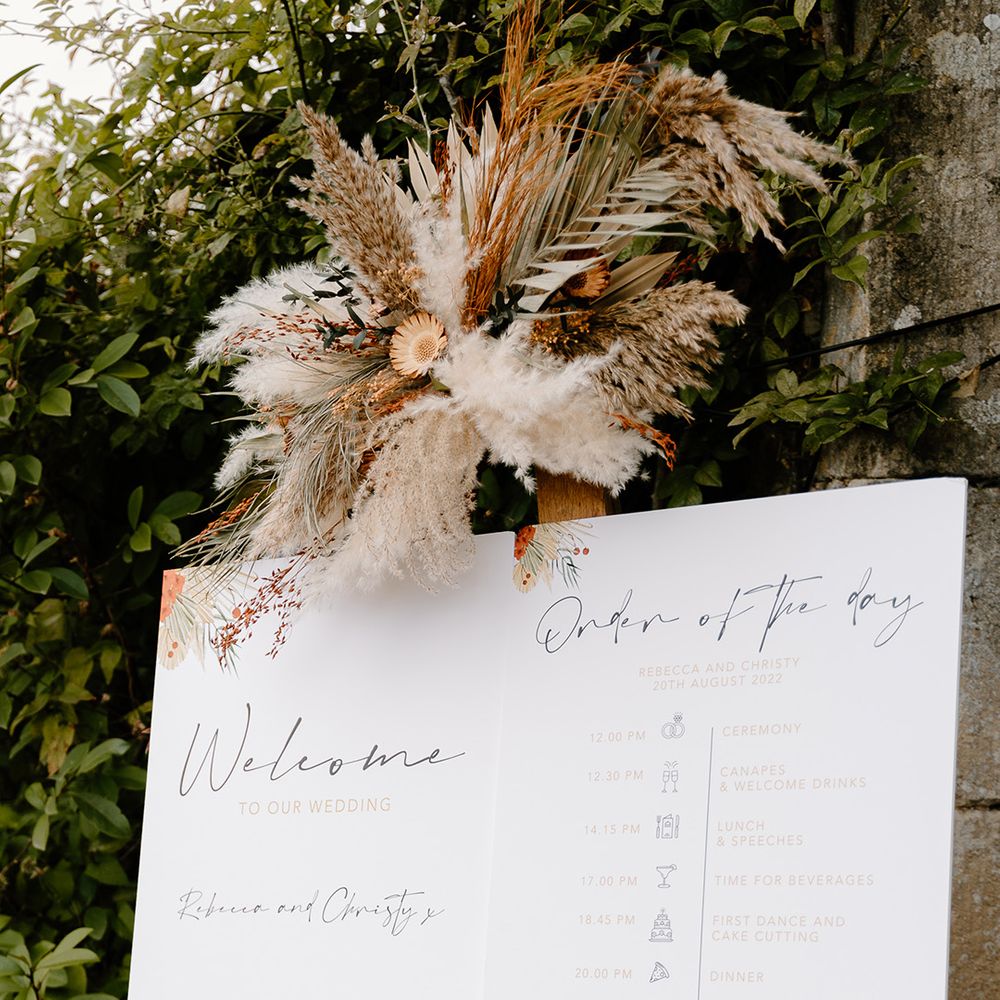 Welcome and order of the day wedding sign with pampas grass decor at The Great Tythe Barn Tetbury