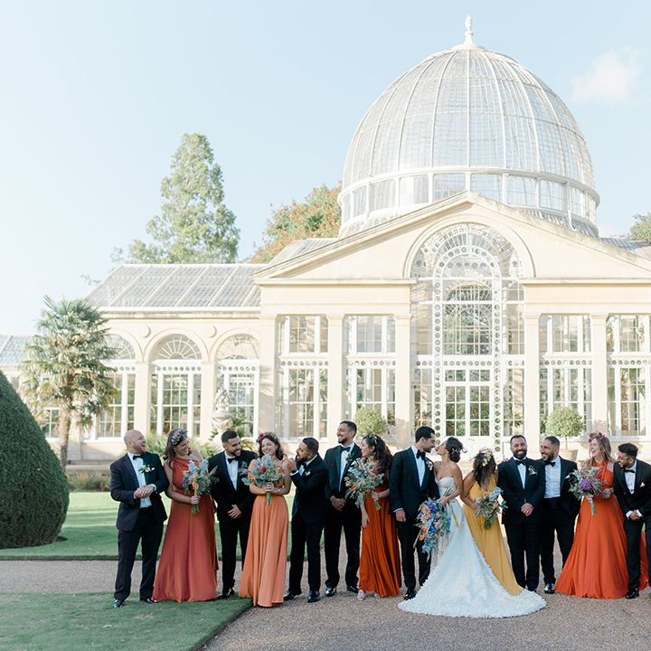 Bride & groom stand with their wedding party outside Syon Park Conservatory 