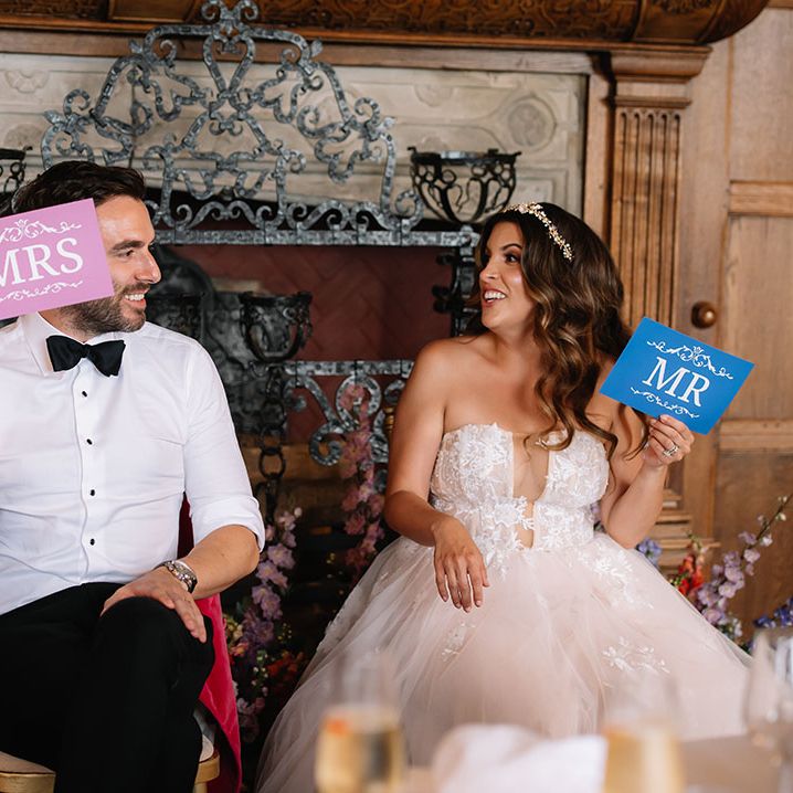 The bride and groom laugh with each other as they play a Mr and Mrs wedding quiz game 