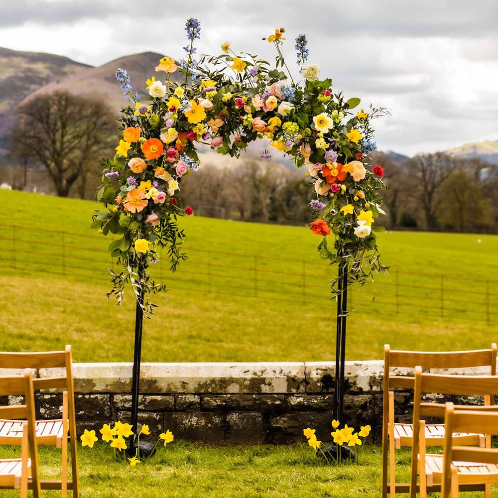 Colourful Spring floral arch for outdoor wedding ceremony at Plas Dinam 