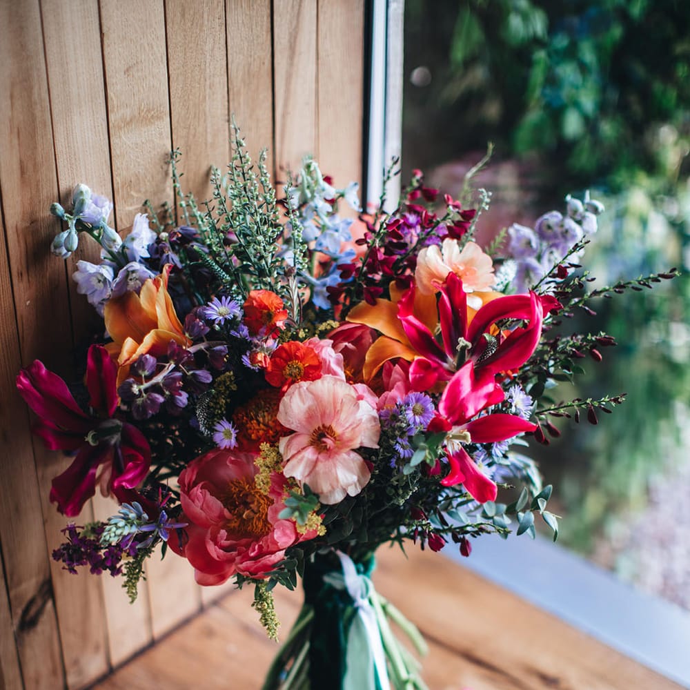 Bright purple, orange, and pink wedding bouquet with lilies, wax flower, and more 