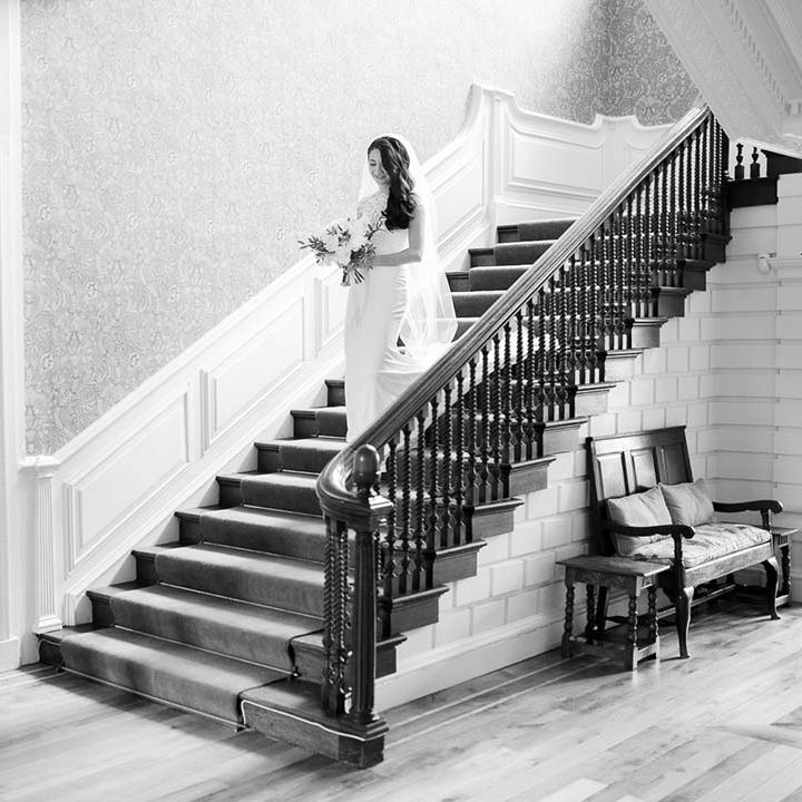 Bride in a Kelly Faetanini walking down the stairs to greet her husband in a navy suit for their 'first look' 