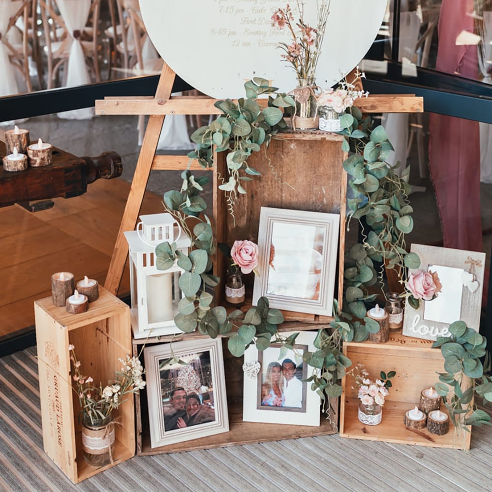 White and gold clock order of the day wedding signage with moveable arms surrounded by wooden crates and family photos 