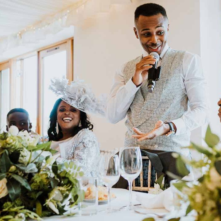 Groom wearing patterned light grey waistcoat doing wedding speech at the high table of Tredudwell Manor 
