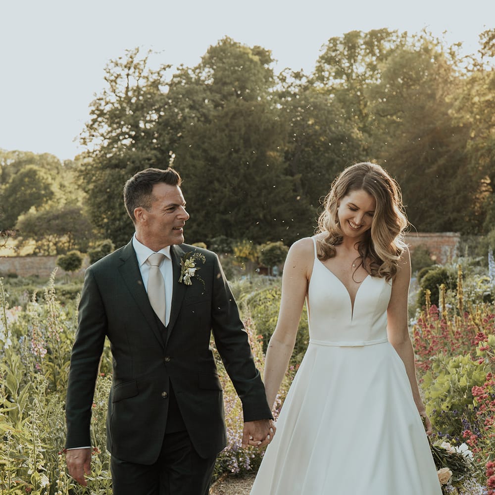 The bride and groom walking through the gardens at Kelmarsh Hall together 