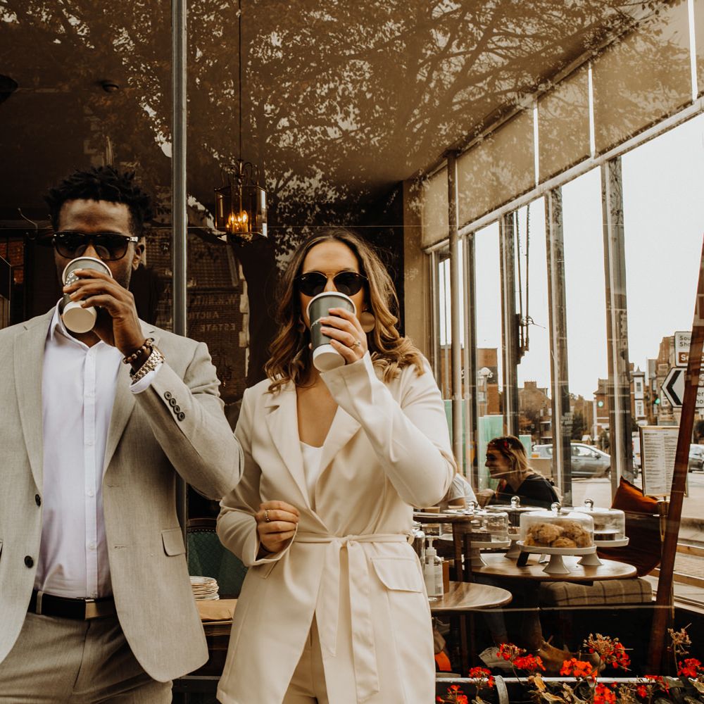 Bride and groom in sunglasses enjoying a coffee at city elopement 