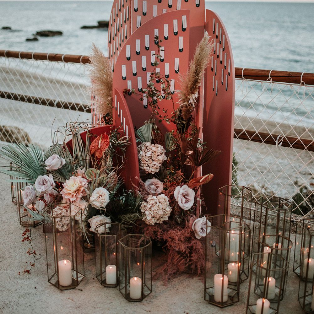 Dusky pink geometric escort card display decorated with lanterns and dried flower arrangements 