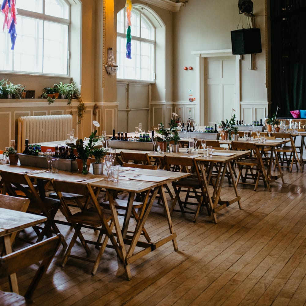 DIY wedding with wooden table and chairs and colourful streamers hanging from the ceiling 
