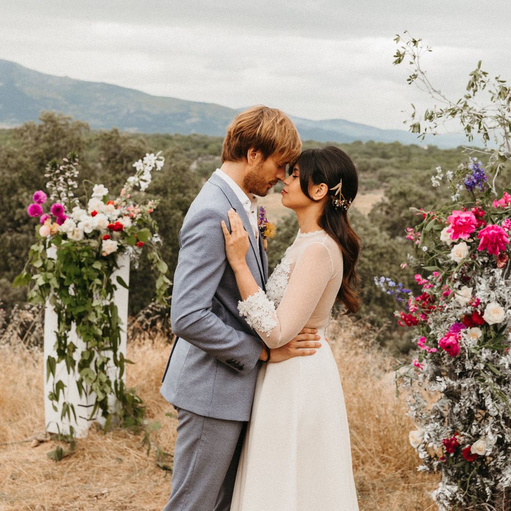 Bride & groom kiss with romantic backdrop and floral pillars