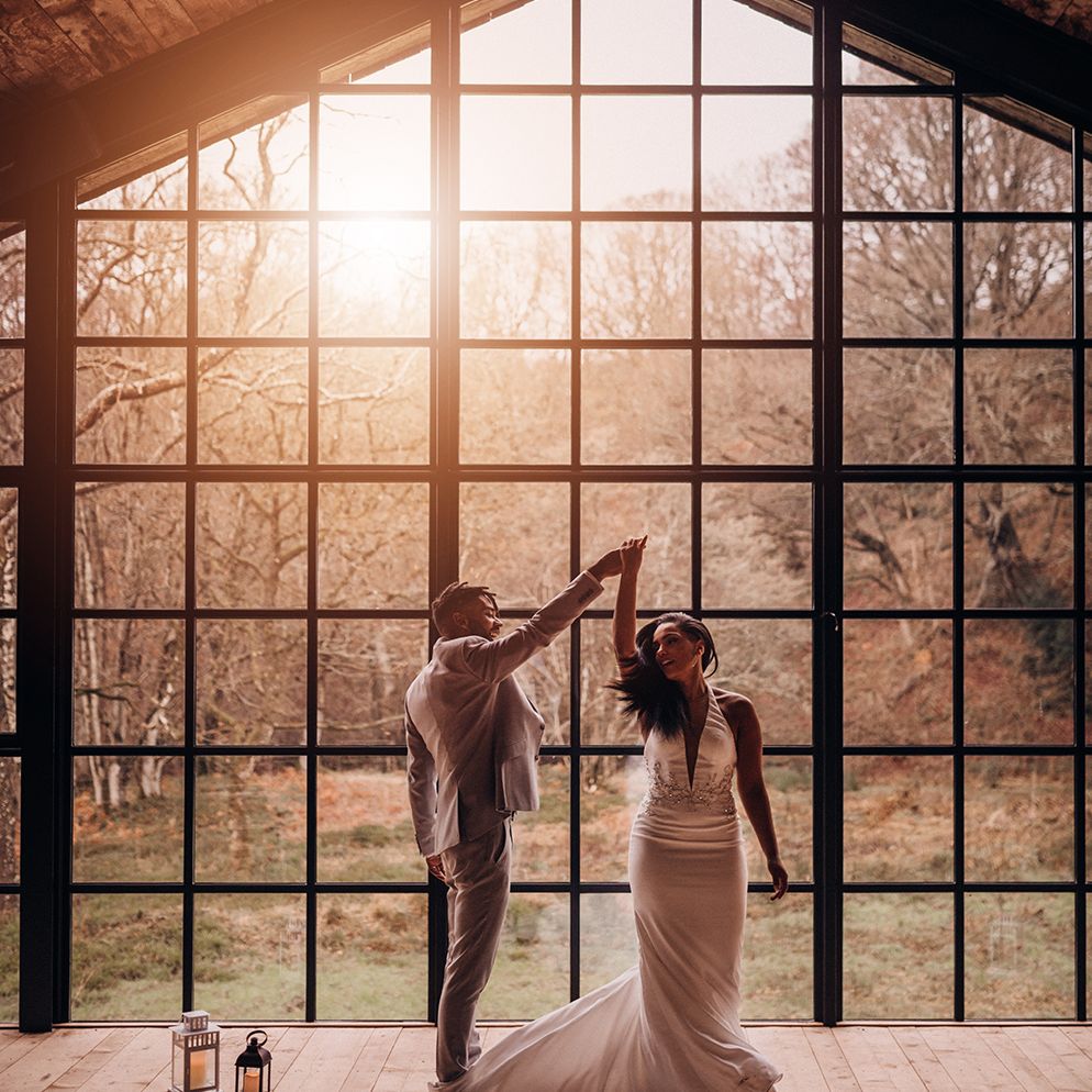 Bride & groom dance in front of large arched window as the sunlight streams through