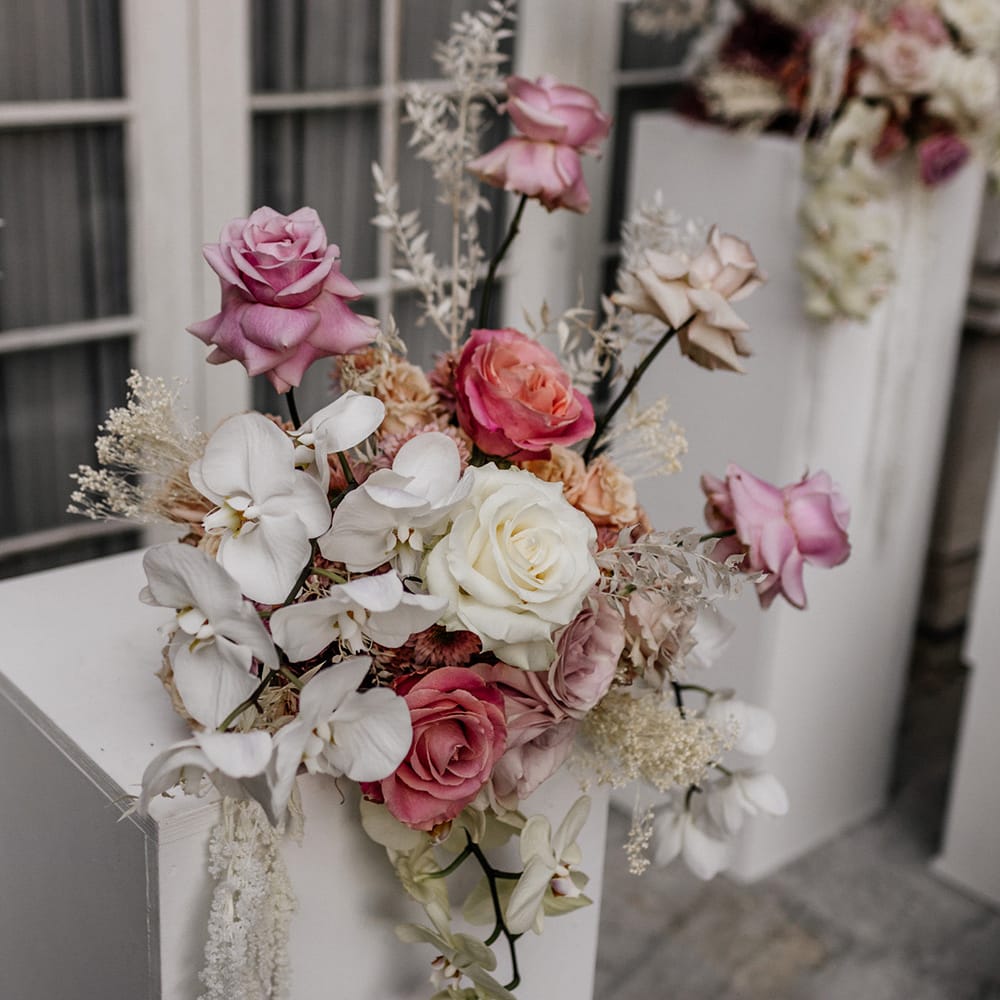 Romantic wedding flower arrangement with white orchids and pink peeled back roses 