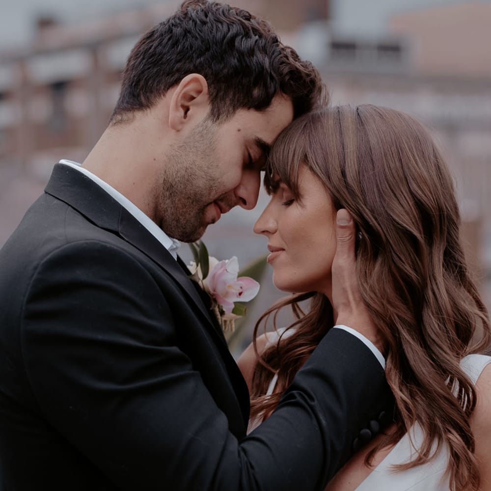 Groom embracing his brides face with long wavy brown hair and fringe 