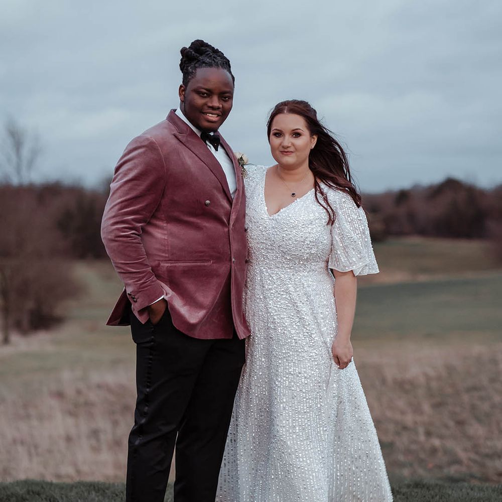 Bride & groom stand on fields on their wedding day